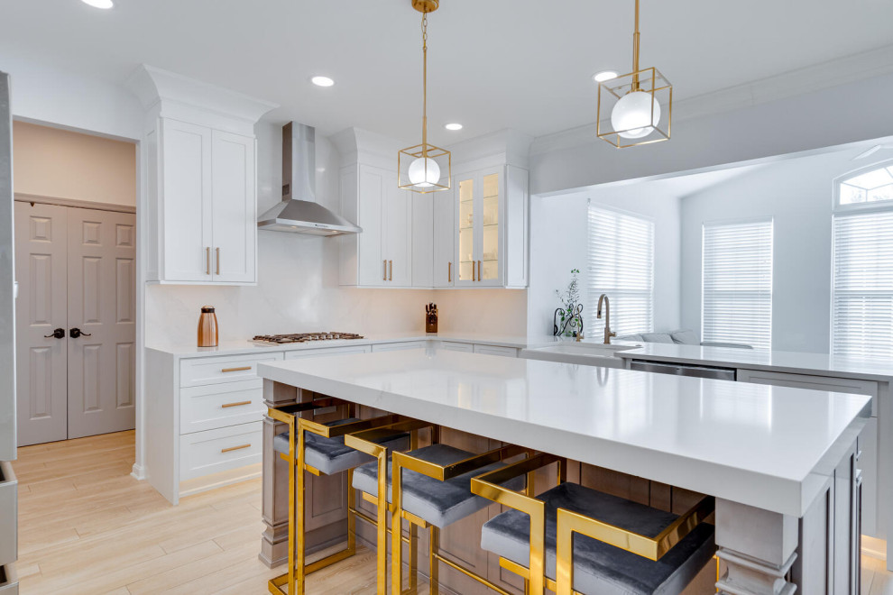This is an example of a medium sized modern l-shaped kitchen/diner in DC Metro with a belfast sink, shaker cabinets, white cabinets, engineered stone countertops, white splashback, engineered quartz splashback, stainless steel appliances, porcelain flooring, an island, beige floors and white worktops.
