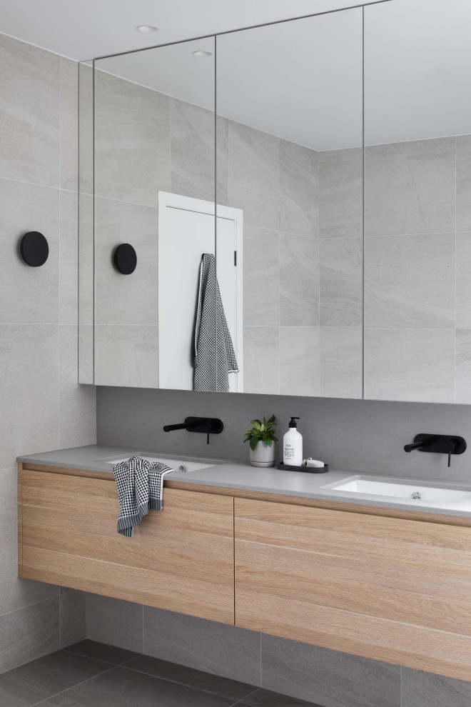 Inspiration for a medium sized contemporary grey and white family bathroom in Melbourne with light wood cabinets, grey tiles, grey walls, a submerged sink, grey floors, grey worktops, double sinks, a floating vanity unit, a freestanding bath and ceramic flooring.
