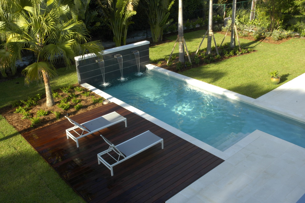 Photo of an expansive modern courtyard l-shaped lap pool in Miami with a water feature and concrete pavers.