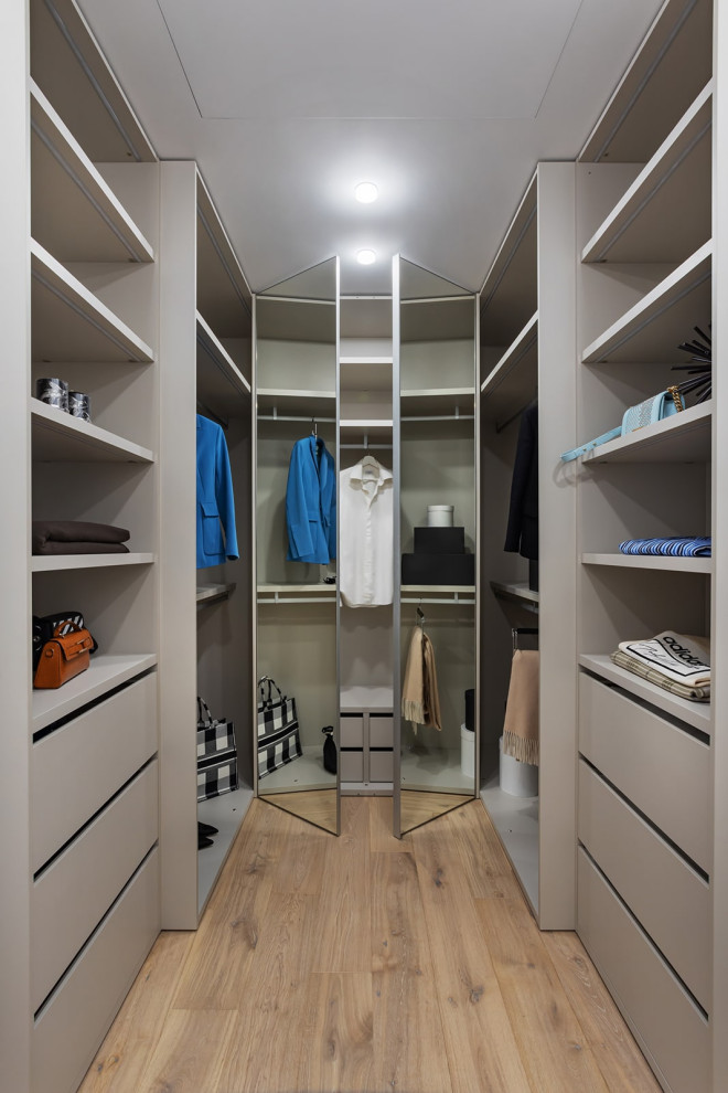 Diseño de armario vestidor unisex contemporáneo de tamaño medio con armarios con paneles lisos, puertas de armario beige, suelo de madera clara y suelo beige