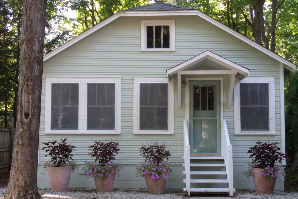 This is an example of a small traditional one-storey green exterior in Chicago with wood siding and a shed roof.