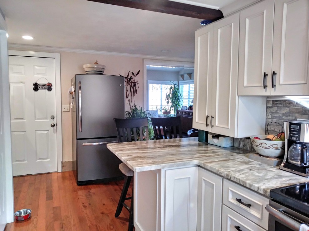 Small modern kitchen pantry in Providence with granite benchtops, grey splashback, stone tile splashback, stainless steel appliances, white benchtop, recessed-panel cabinets, white cabinets, laminate floors, no island and brown floor.