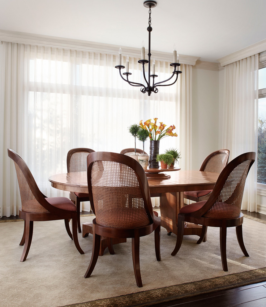 This is an example of a traditional dining room in Milwaukee with white walls and dark hardwood floors.