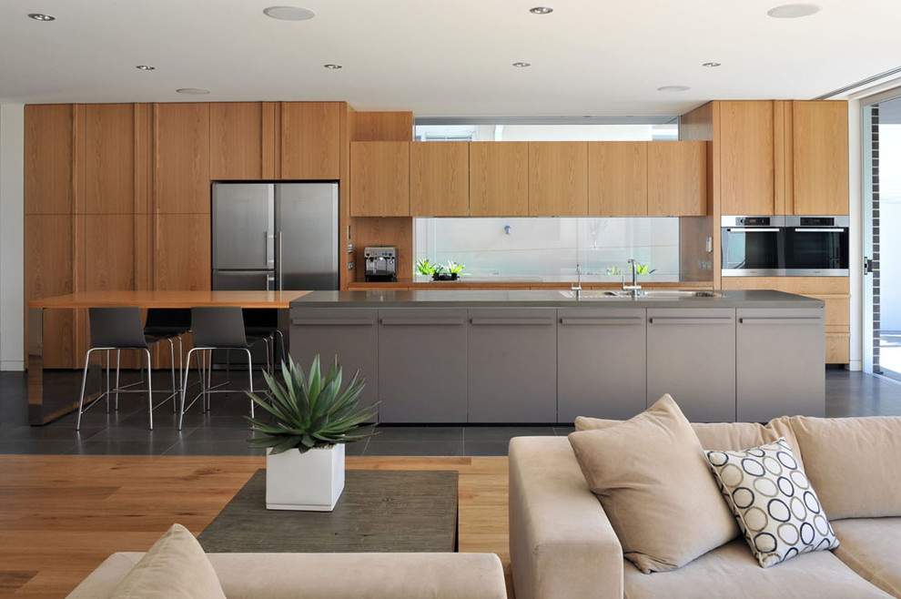 Design ideas for a mid-sized contemporary galley open plan kitchen in Sydney with a double-bowl sink, flat-panel cabinets, light wood cabinets, glass sheet splashback, stainless steel appliances and with island.
