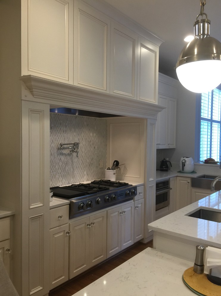 Example of a large transitional u-shaped medium tone wood floor open concept kitchen design in DC Metro with an undermount sink, raised-panel cabinets, white cabinets, quartzite countertops, stainless steel appliances and an island
