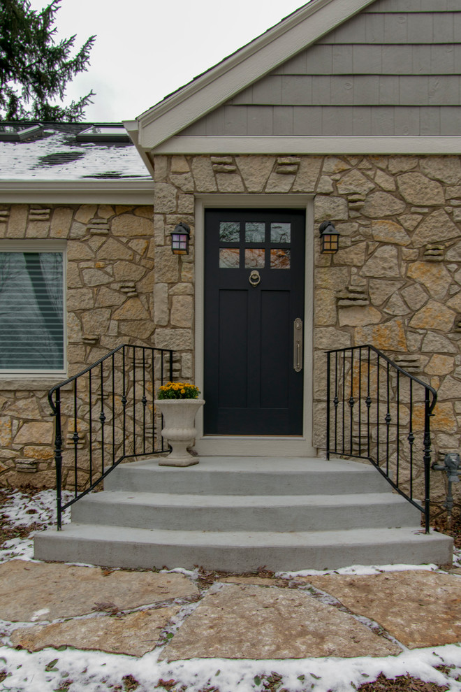 This is an example of a small transitional two-storey grey house exterior in Milwaukee with stone veneer, a gable roof and a shingle roof.