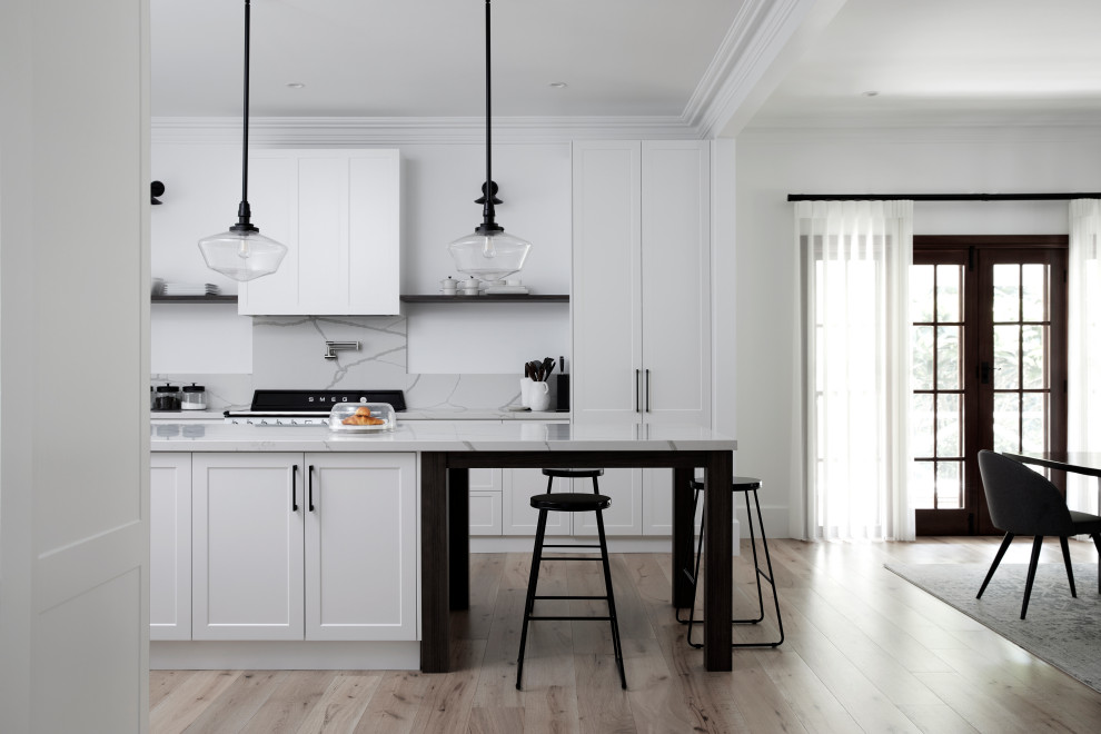 Photo of a shabby-chic style eat-in kitchen in Sydney with a farmhouse sink, quartz benchtops, white splashback, engineered quartz splashback, white appliances, light hardwood floors, with island, beige floor and white benchtop.