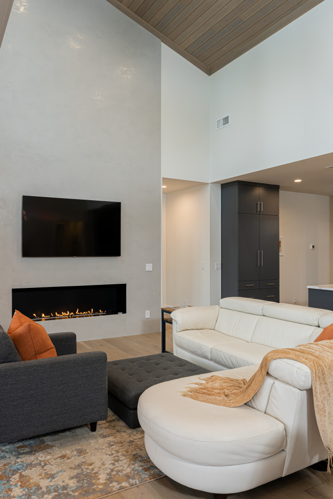 На фото: открытая гостиная комната среднего размера в стиле модернизм с белыми стенами, светлым паркетным полом, горизонтальным камином, фасадом камина из штукатурки, телевизором на стене, бежевым полом и деревянным потолком