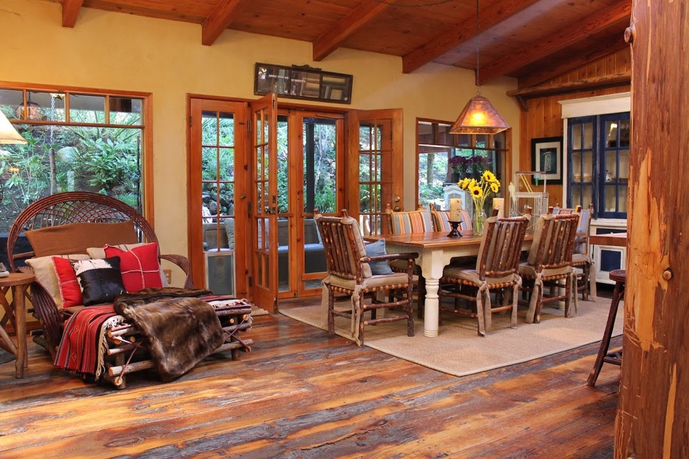 Photo of a country dining room in Los Angeles with yellow walls, dark hardwood floors and brown floor.