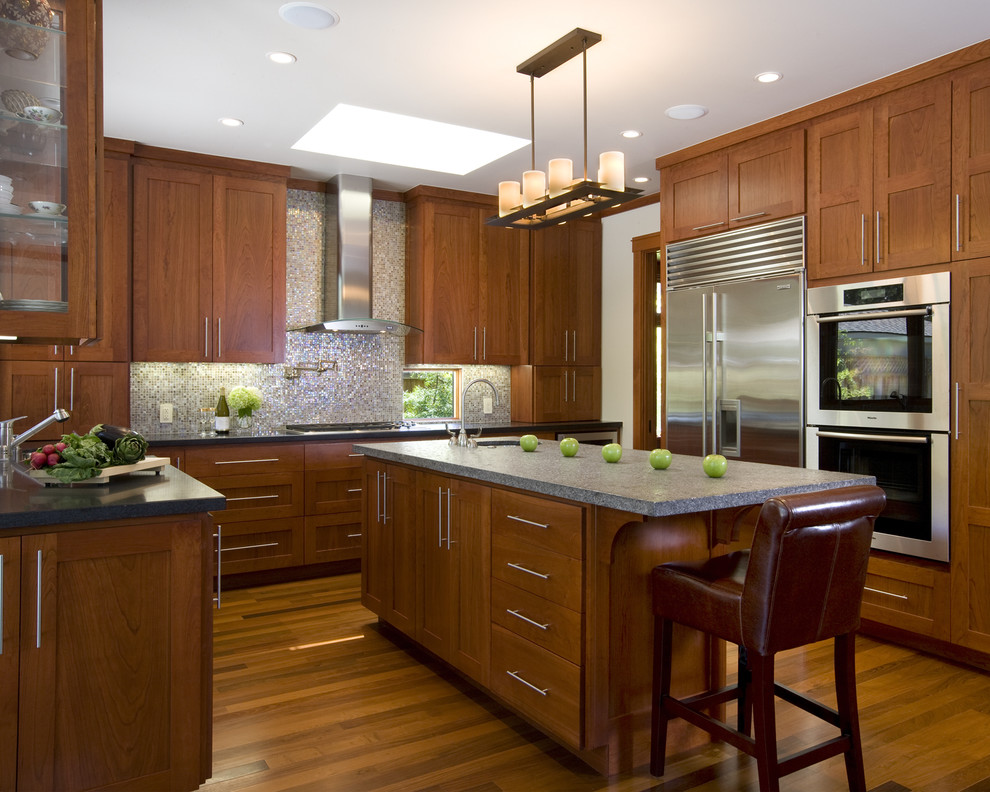 This is an example of an arts and crafts u-shaped separate kitchen in San Francisco with stainless steel appliances, recessed-panel cabinets, medium wood cabinets, an undermount sink, limestone benchtops and metallic splashback.