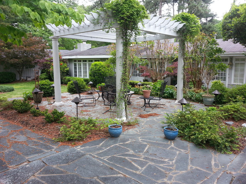 Inspiration for a mid-sized traditional backyard patio in Raleigh with natural stone pavers and a pergola.