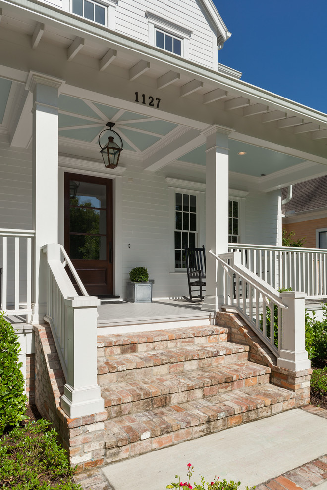 Huge country wood railing front porch idea in Houston with a roof extension