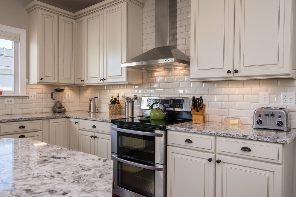 Large country u-shaped separate kitchen in DC Metro with raised-panel cabinets, white cabinets, granite benchtops, white splashback, subway tile splashback, stainless steel appliances, dark hardwood floors, with island, brown floor, grey benchtop and a farmhouse sink.