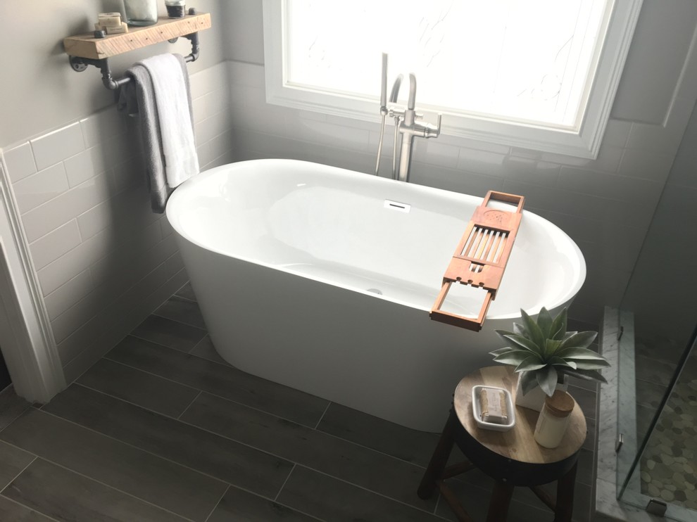 Design ideas for a mid-sized transitional master bathroom in Other with shaker cabinets, grey cabinets, a freestanding tub, a corner shower, a one-piece toilet, white tile, subway tile, grey walls, laminate floors, a vessel sink, grey floor and a hinged shower door.