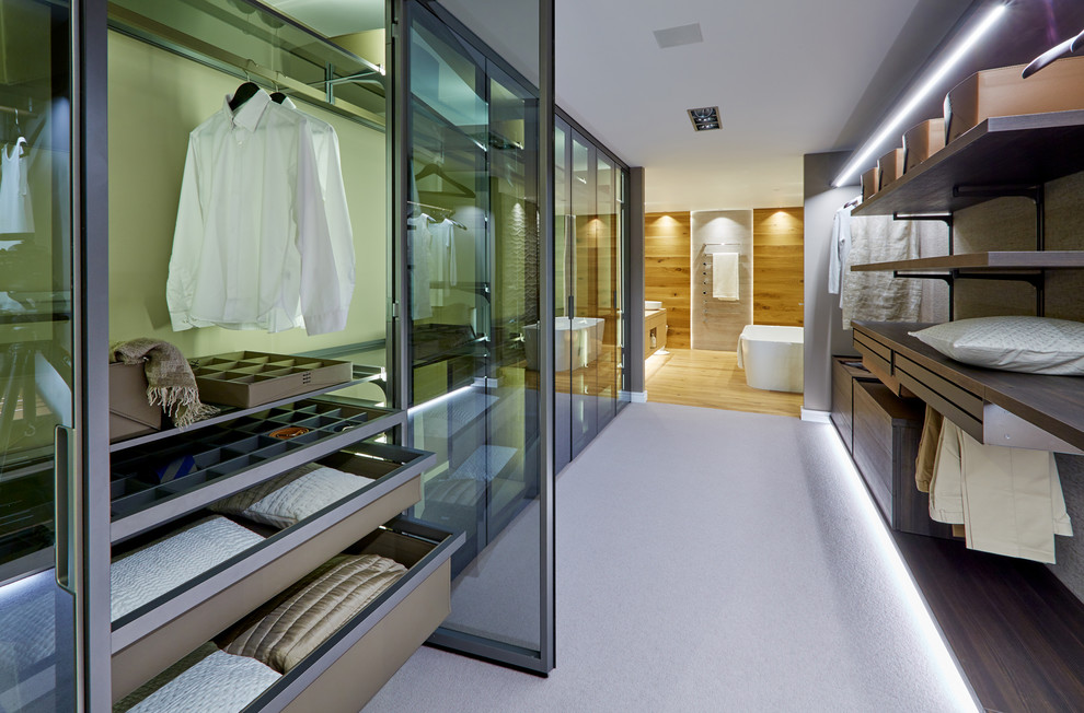 Large contemporary gender-neutral walk-in wardrobe in Wiltshire with flat-panel cabinets, dark wood cabinets, carpet and white floor.