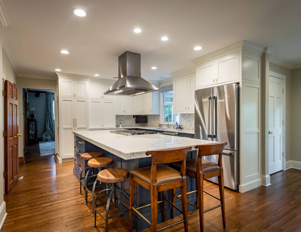 This is an example of a mid-sized traditional l-shaped separate kitchen in Chicago with a drop-in sink, shaker cabinets, white cabinets, quartz benchtops, grey splashback, ceramic splashback, stainless steel appliances, light hardwood floors, with island, brown floor, white benchtop and wallpaper.