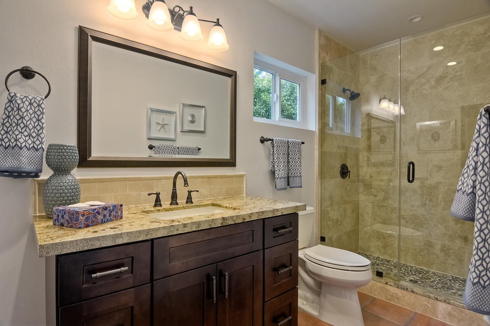 Photo of a mid-sized master bathroom in San Diego with an undermount sink, shaker cabinets, dark wood cabinets, marble benchtops, an open shower, a two-piece toilet, beige tile, stone tile, beige walls and terra-cotta floors.