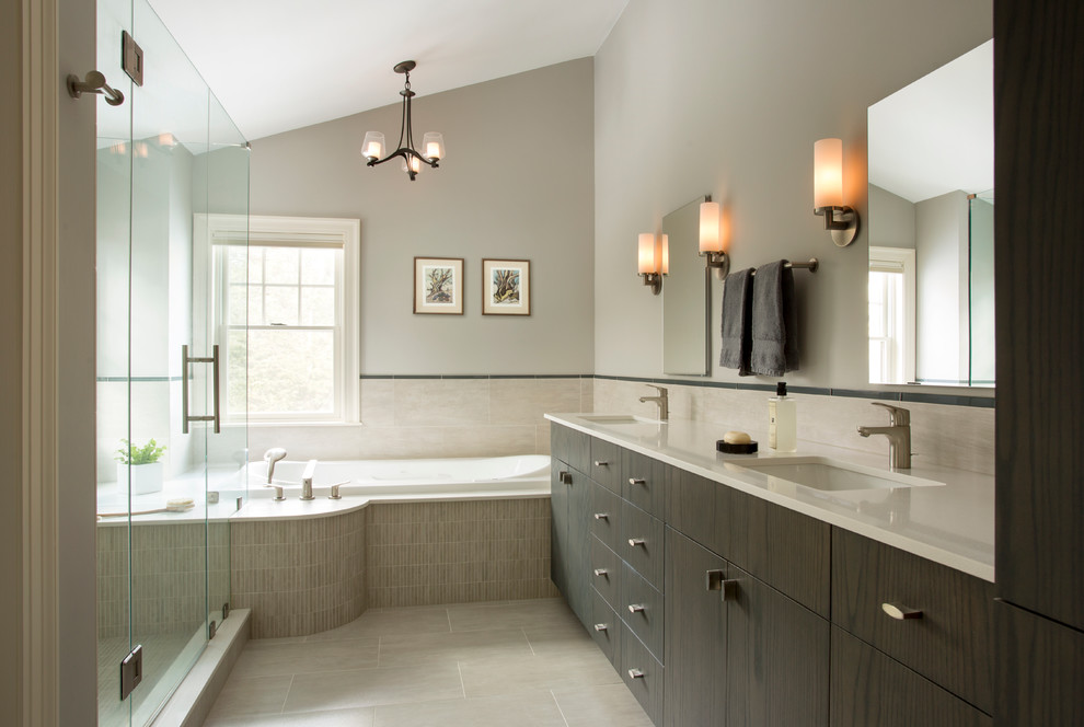 This is an example of a contemporary bathroom in Boston with an undermount sink, flat-panel cabinets, dark wood cabinets, a drop-in tub, a corner shower, gray tile and grey walls.