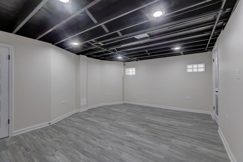 This is an example of a mid-sized industrial basement in Chicago with laminate floors, grey floor and exposed beam.