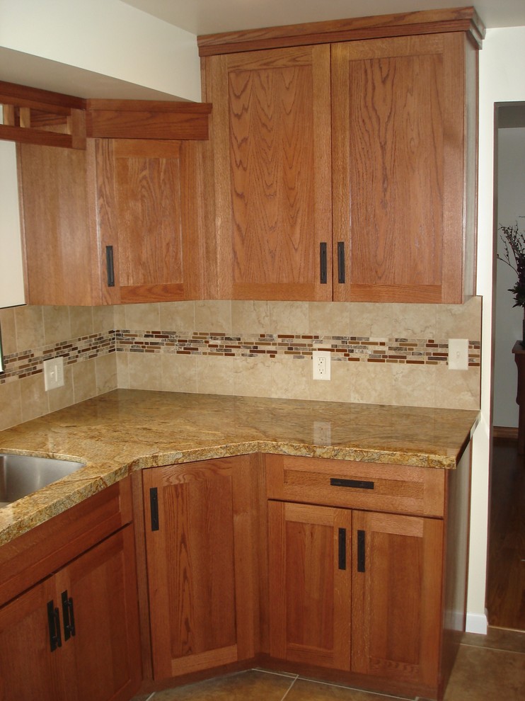 Photo of a mid-sized transitional u-shaped separate kitchen in Other with shaker cabinets, medium wood cabinets, granite benchtops, beige splashback, mosaic tile splashback, a double-bowl sink, stainless steel appliances, porcelain floors, no island and brown floor.