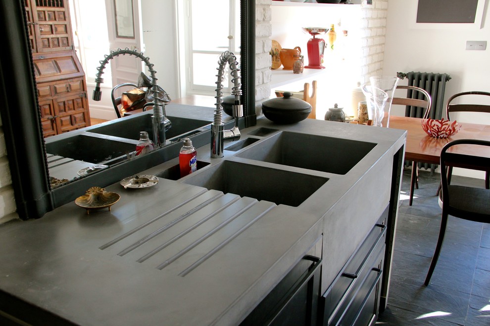 Large industrial u-shaped separate kitchen in Paris with a double-bowl sink, beaded inset cabinets, black cabinets, concrete benchtops, black splashback, slate splashback, black appliances, slate floors, multiple islands, black floor and grey benchtop.