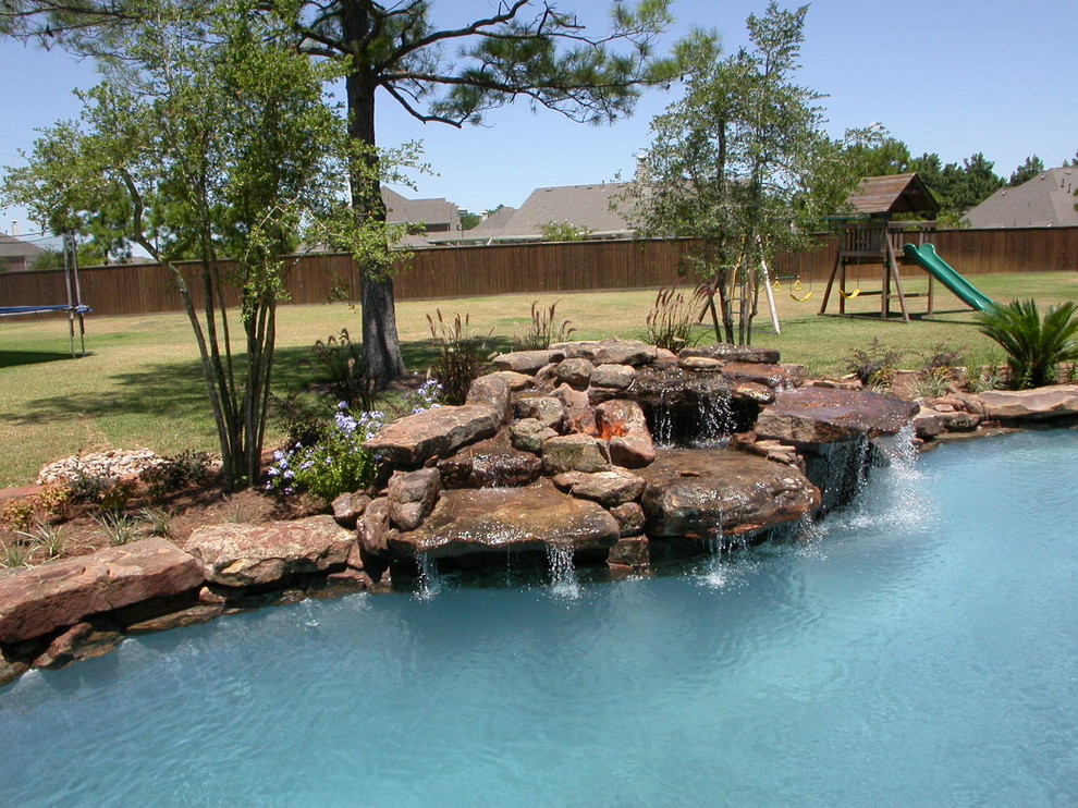 Design ideas for a large traditional courtyard custom-shaped natural pool in Houston with a water feature and gravel.