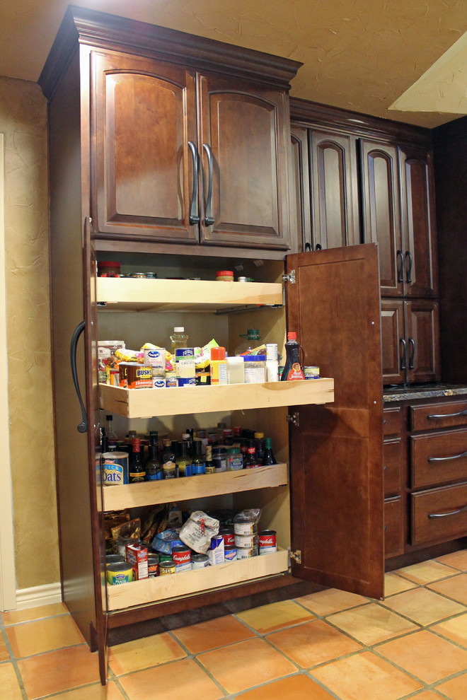 This is an example of a mid-sized traditional u-shaped kitchen pantry in Austin with an undermount sink, raised-panel cabinets, dark wood cabinets, granite benchtops, beige splashback, stone tile splashback, stainless steel appliances, terra-cotta floors and no island.