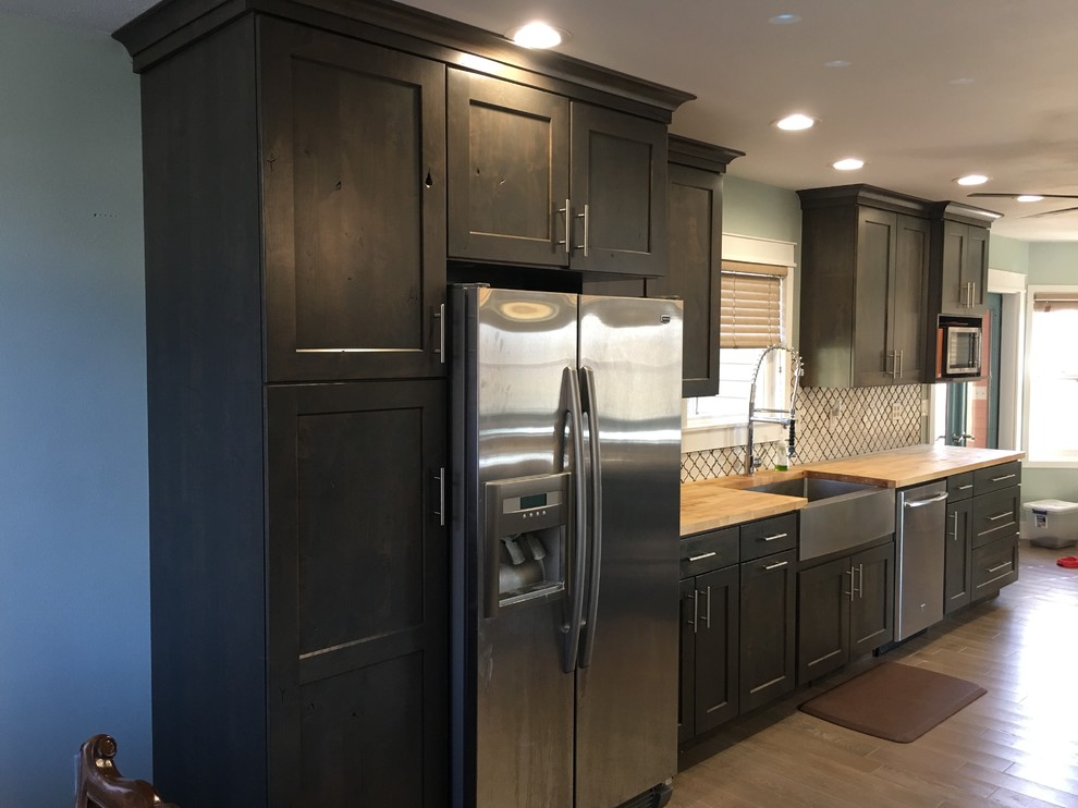 Eat-in kitchen - large contemporary single-wall dark wood floor and brown floor eat-in kitchen idea with a farmhouse sink, shaker cabinets, dark wood cabinets, quartzite countertops, multicolored backsplash, porcelain backsplash, stainless steel appliances and an island