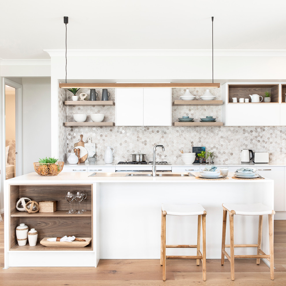 Inspiration for a mid-sized beach style galley open plan kitchen in Other with a double-bowl sink, white cabinets, quartz benchtops, brown splashback, mosaic tile splashback, stainless steel appliances, medium hardwood floors, with island, brown floor and white benchtop.