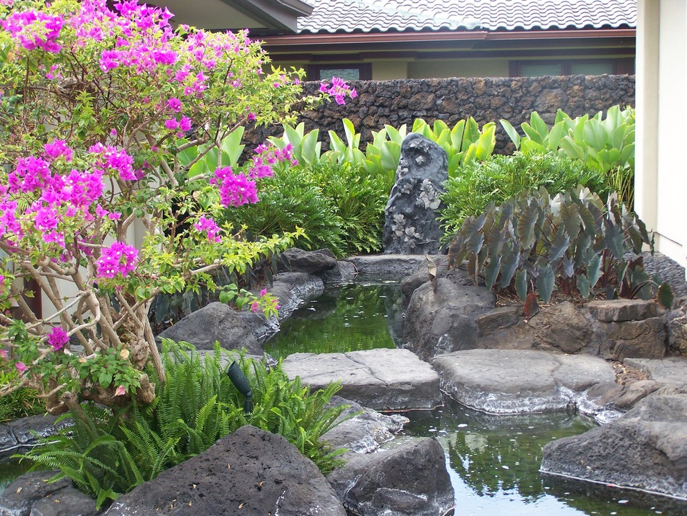 Photo of a mid-sized tropical courtyard garden in Hawaii with with pond and natural stone pavers.