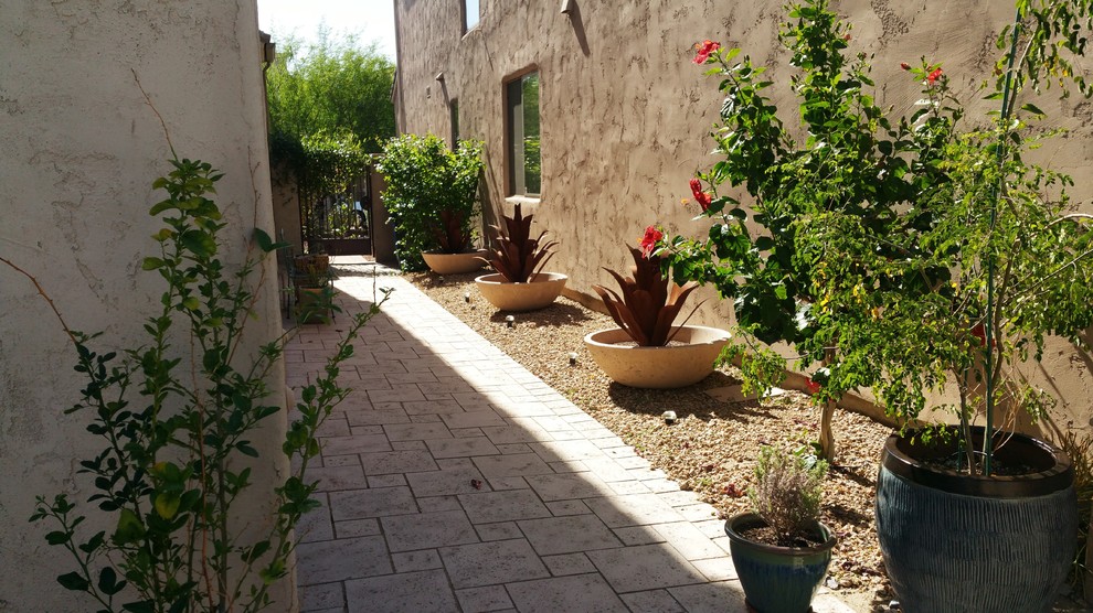 This is an example of a mediterranean side yard patio in Phoenix with no cover and natural stone pavers.