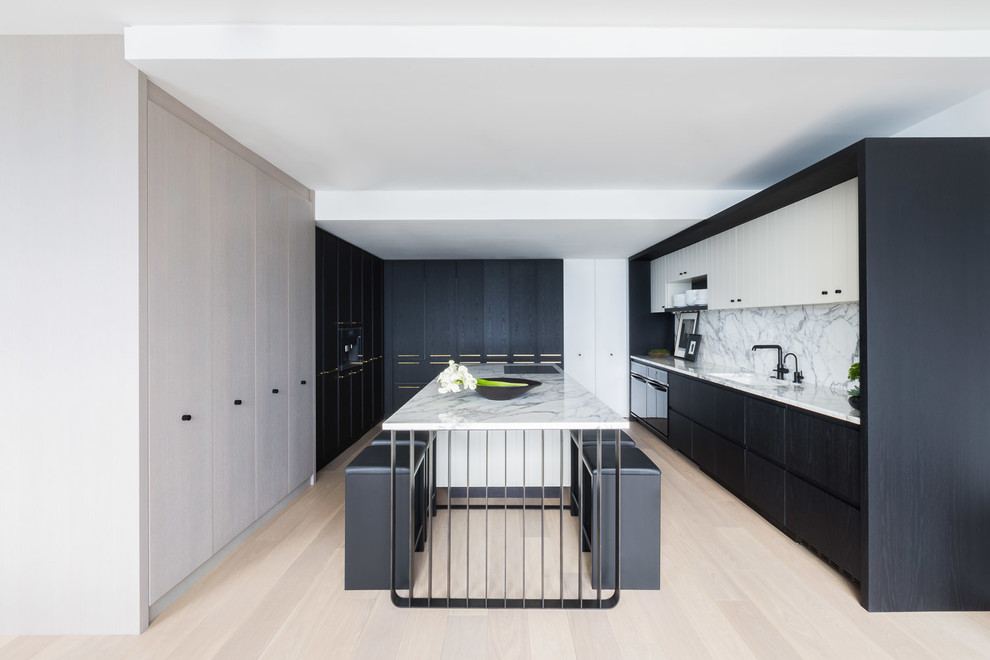 Photo of a mid-sized contemporary kitchen in Chicago with a single-bowl sink, flat-panel cabinets, black cabinets, marble benchtops, white splashback, marble splashback, light hardwood floors, with island and beige floor.