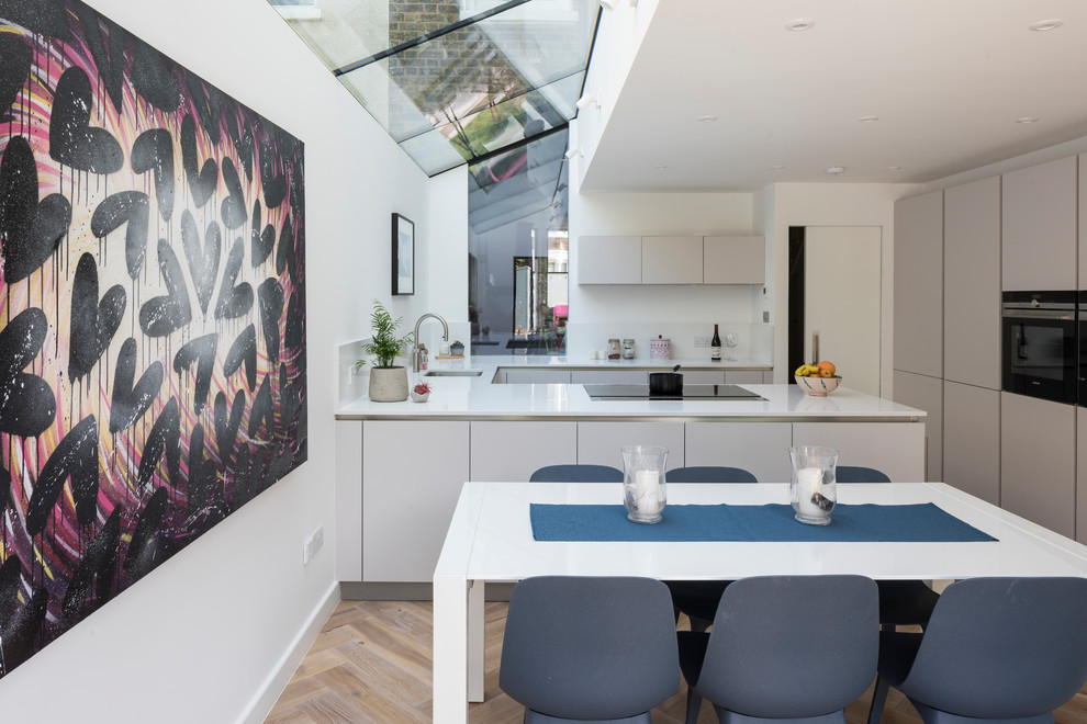 This is an example of a contemporary kitchen/dining combo in London with white walls, light hardwood floors and beige floor.