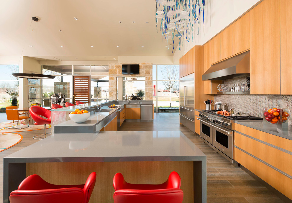 Design ideas for an expansive midcentury open plan kitchen in Dallas with an undermount sink, flat-panel cabinets, light wood cabinets, quartzite benchtops, glass tile splashback, stainless steel appliances, porcelain floors, brown floor and multiple islands.