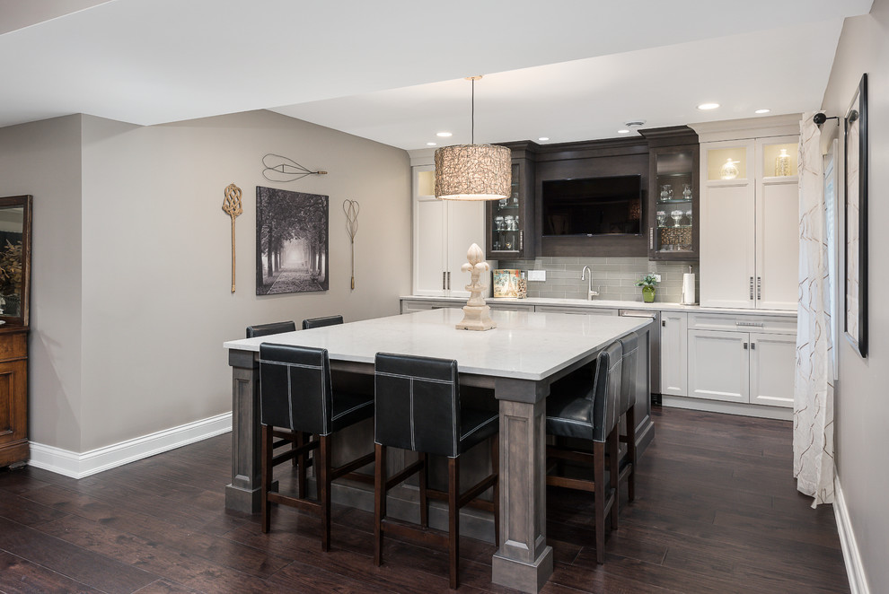 Photo of a traditional seated home bar in Chicago with shaker cabinets, white cabinets, grey splashback, subway tile splashback, dark hardwood floors, brown floor and white benchtop.