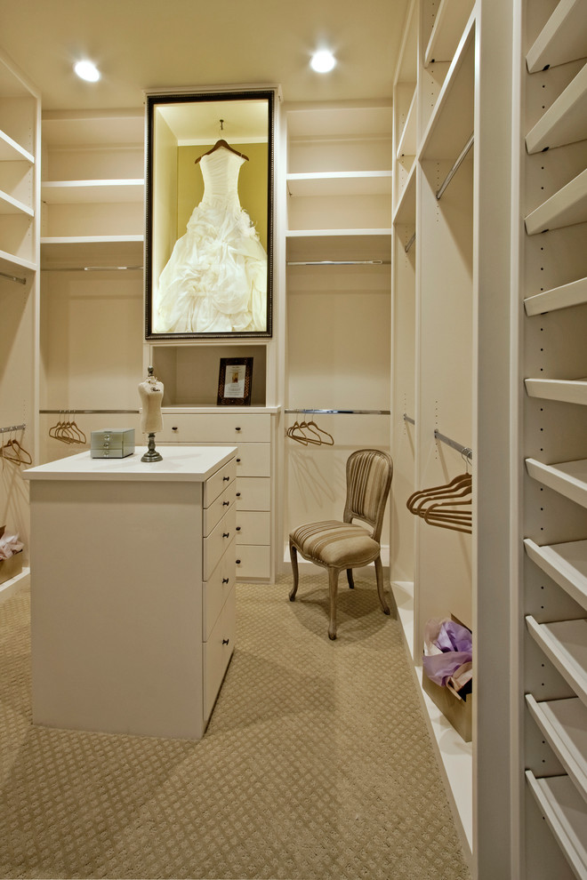 This is an example of a large traditional women's walk-in wardrobe in Houston with carpet.
