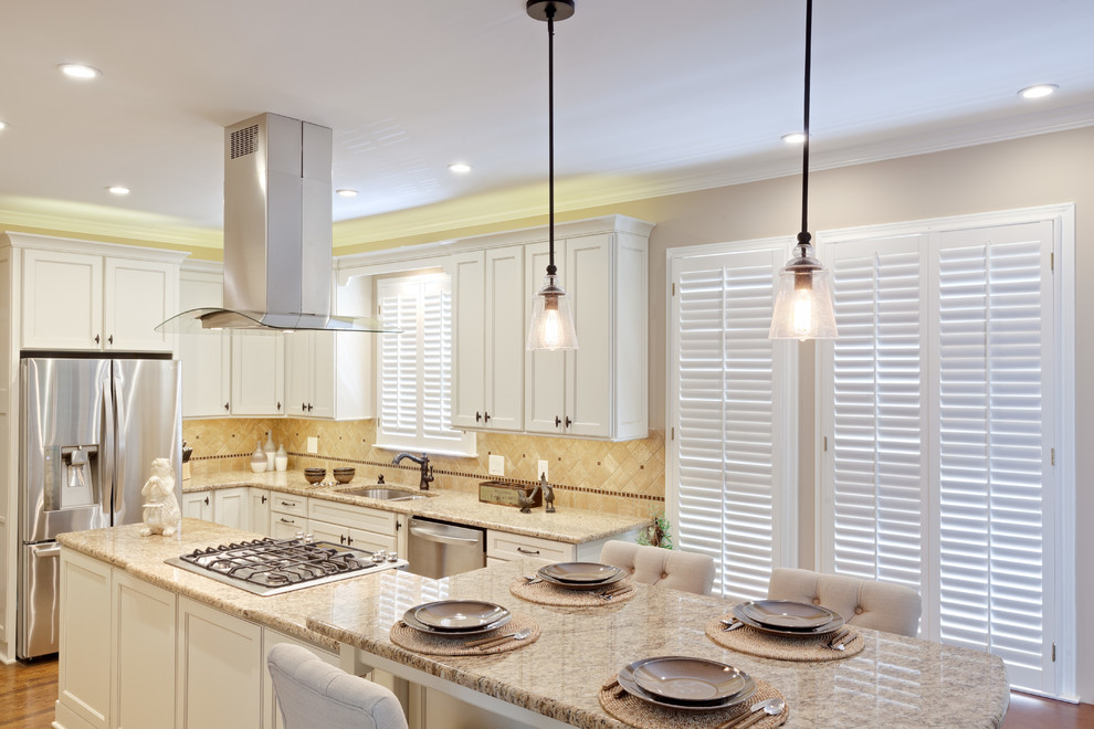 Large traditional galley eat-in kitchen in Atlanta with an undermount sink, recessed-panel cabinets, white cabinets, granite benchtops, beige splashback, stone tile splashback, stainless steel appliances, medium hardwood floors, with island, brown floor and beige benchtop.