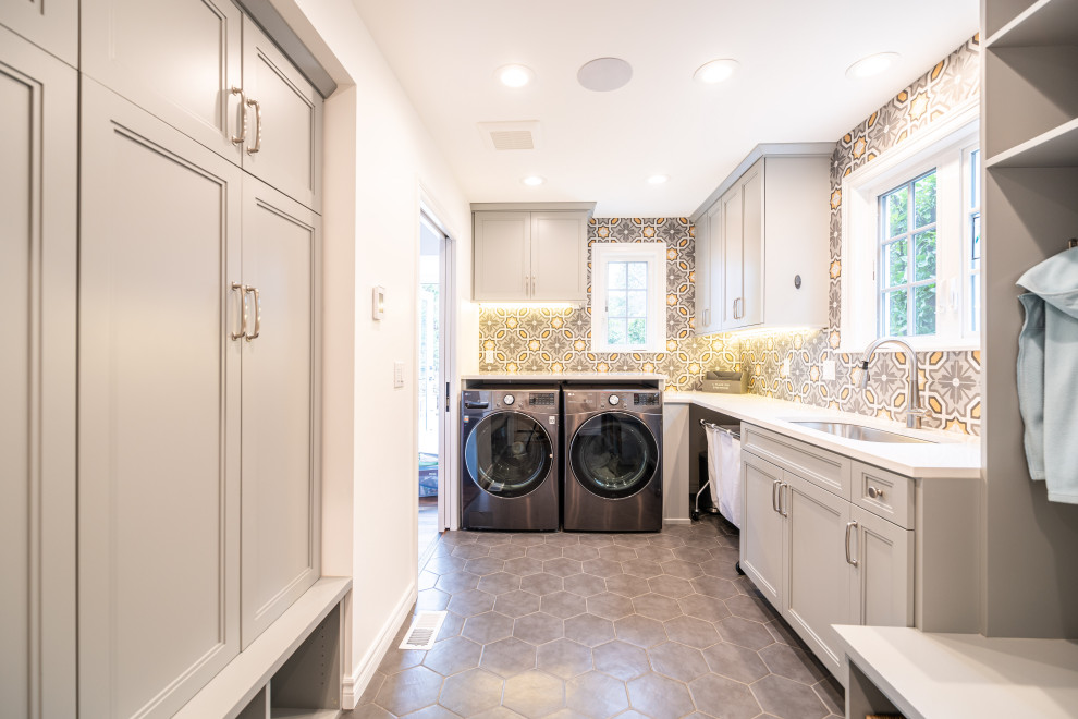 Large minimalist u-shaped ceramic tile and gray floor utility room photo in Seattle with an undermount sink, flat-panel cabinets, gray cabinets, quartz countertops, gray backsplash, ceramic backsplash, multicolored walls, a side-by-side washer/dryer and white countertops