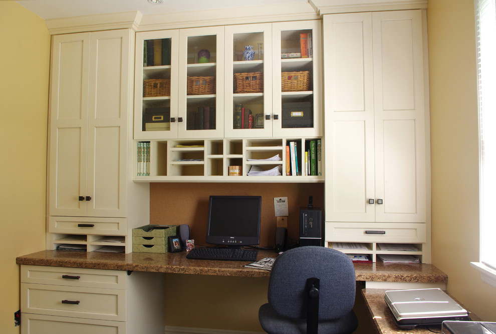 This is an example of a small traditional home office in New York with a built-in desk and yellow walls.