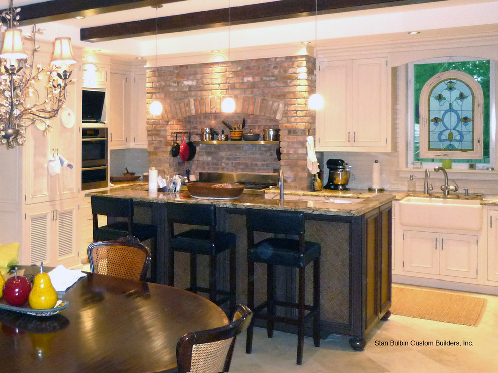 Large traditional u-shaped eat-in kitchen in Miami with a farmhouse sink, beaded inset cabinets, beige cabinets, granite benchtops, beige splashback, subway tile splashback, panelled appliances, limestone floors, with island and beige floor.