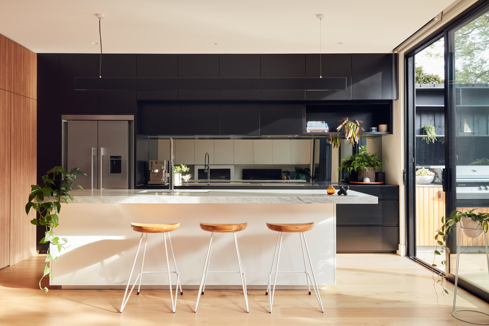 Design ideas for a modern kitchen in Melbourne with mirror splashback and stainless steel appliances.