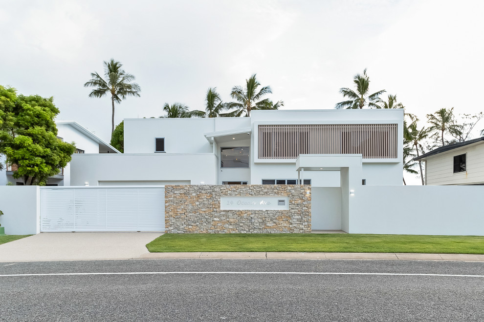 Large beach style two-storey white house exterior in Other with a flat roof.