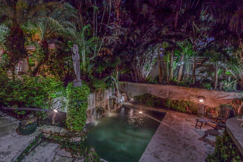 Inspiration for a mid-sized tropical courtyard rectangular natural pool in Miami with a water feature and natural stone pavers.