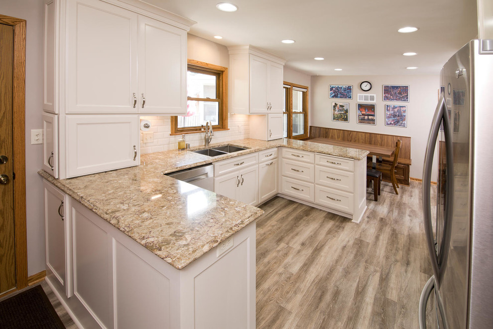 Design ideas for a mid-sized traditional u-shaped eat-in kitchen in Minneapolis with a double-bowl sink, recessed-panel cabinets, white cabinets, granite benchtops, white splashback, subway tile splashback, stainless steel appliances, vinyl floors and no island.
