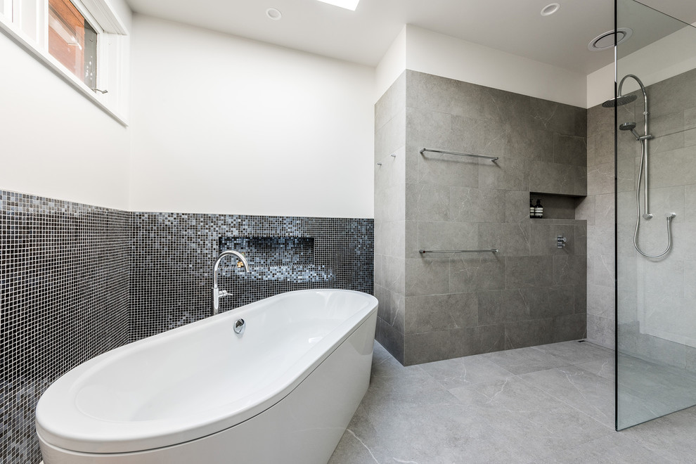 Contemporary bathroom in Melbourne with medium wood cabinets, a freestanding tub, an open shower, gray tile, porcelain tile, a vessel sink, engineered quartz benchtops, a one-piece toilet, white walls and porcelain floors.