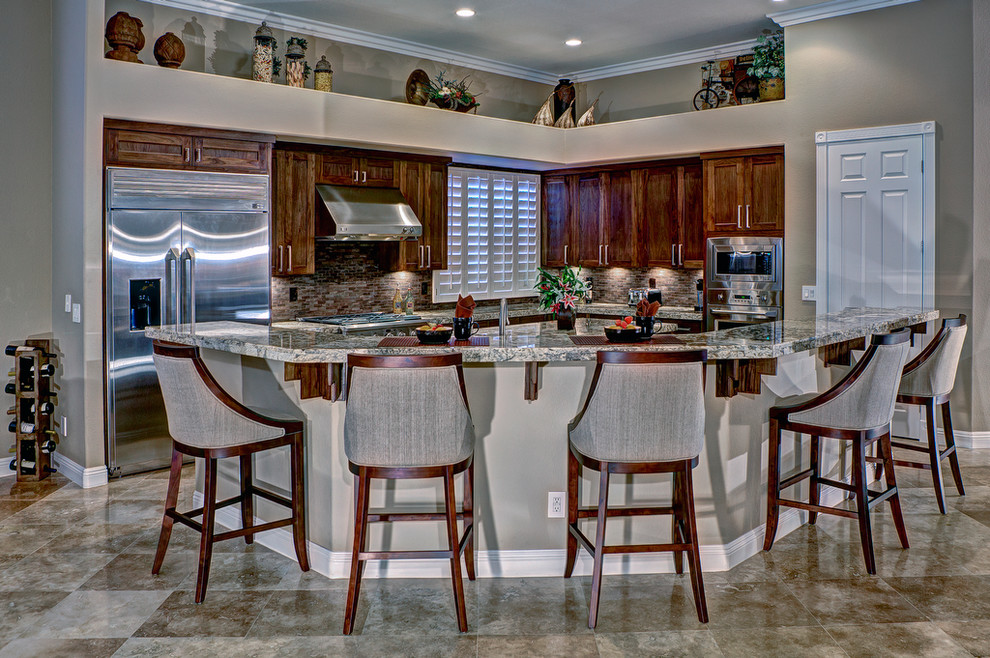 Photo of a mid-sized contemporary l-shaped eat-in kitchen in Las Vegas with shaker cabinets, medium wood cabinets, brown splashback, stainless steel appliances, granite benchtops, stone tile splashback, porcelain floors and with island.