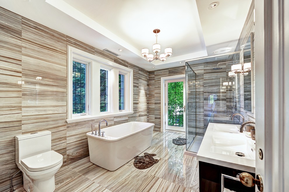 Design ideas for a large contemporary master bathroom in Montreal with dark wood cabinets, a freestanding tub, an alcove shower, a two-piece toilet, beige walls, marble floors, an integrated sink, engineered quartz benchtops, flat-panel cabinets and a hinged shower door.