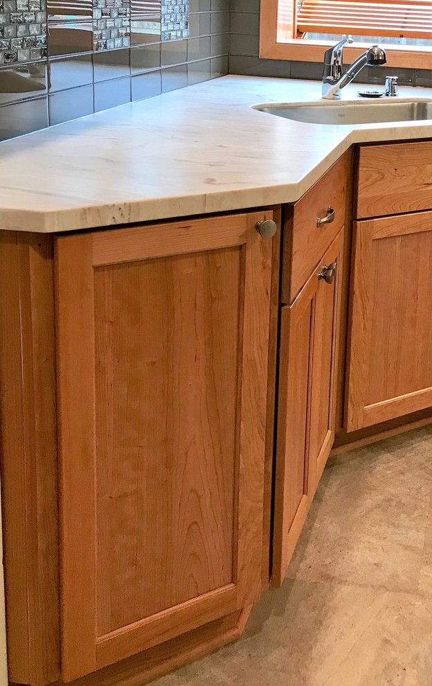 Eat-in kitchen - small transitional galley beige floor eat-in kitchen idea with an undermount sink, recessed-panel cabinets, light wood cabinets, solid surface countertops, brown backsplash, glass tile backsplash, stainless steel appliances and multicolored countertops