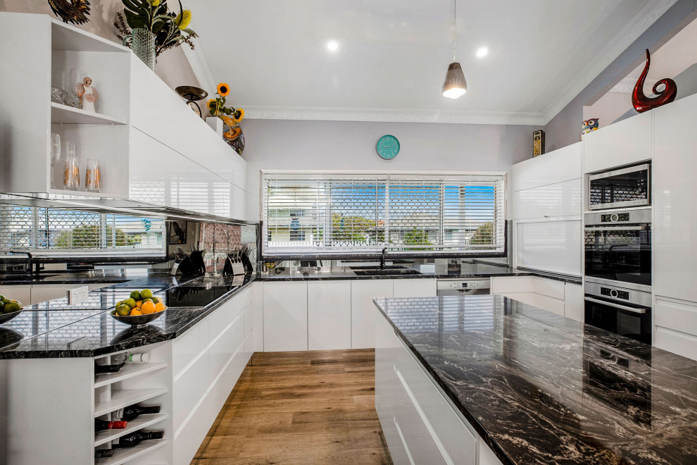 Inspiration for a modern eat-in kitchen in Sunshine Coast with white cabinets, granite benchtops and glass sheet splashback.