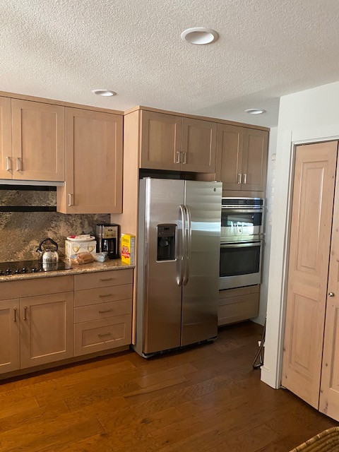 Mid-sized elegant u-shaped medium tone wood floor and brown floor enclosed kitchen photo with a single-bowl sink, shaker cabinets, light wood cabinets, granite countertops, brown backsplash, granite backsplash, stainless steel appliances, a peninsula and brown countertops